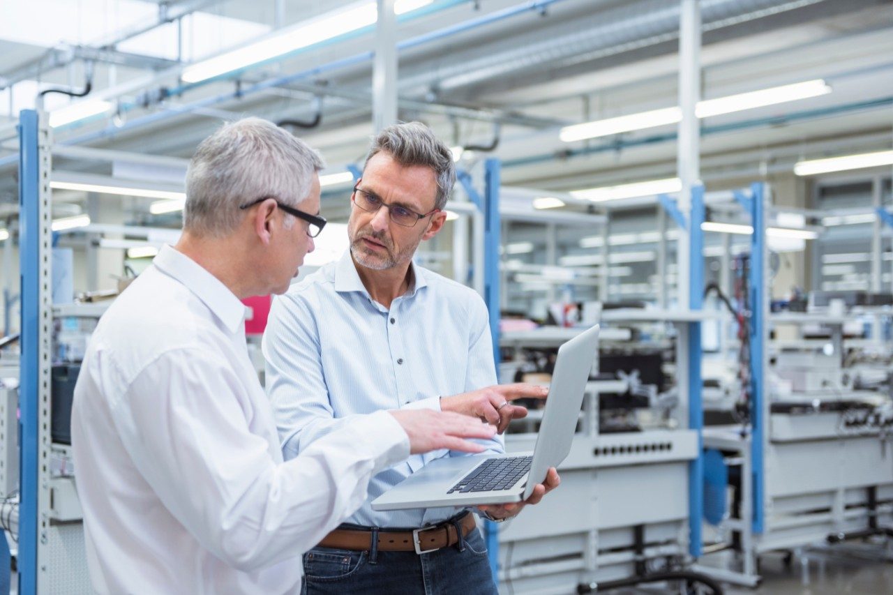 two men talking over a tablet